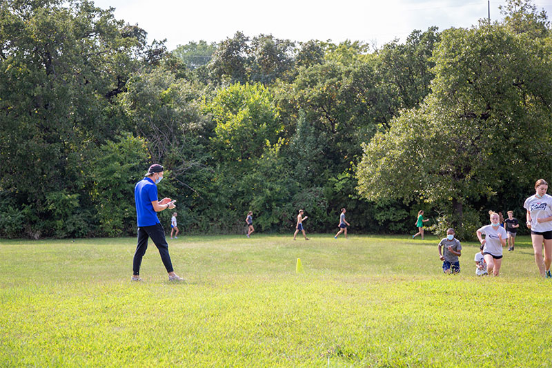 Coach Moon cheering on his Classen SAS at Northeast High School cross country team while they practice a Lacy Park in Oklahoma City