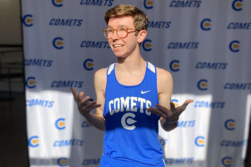 Classen SAS High School at Northeast cross country and track athlete Aiden Kirkpatrick standing against a Classen SAS photo backdrop