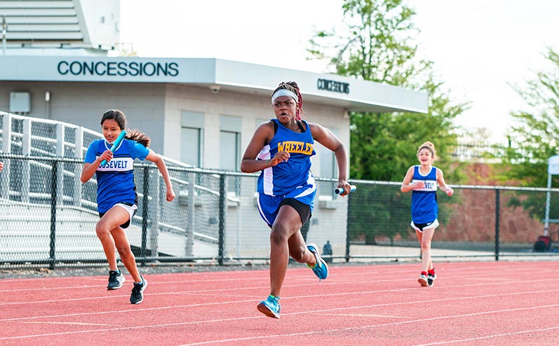 Fields & Futures All-City Track Meet Blog female middle school athletes competing in a relay race