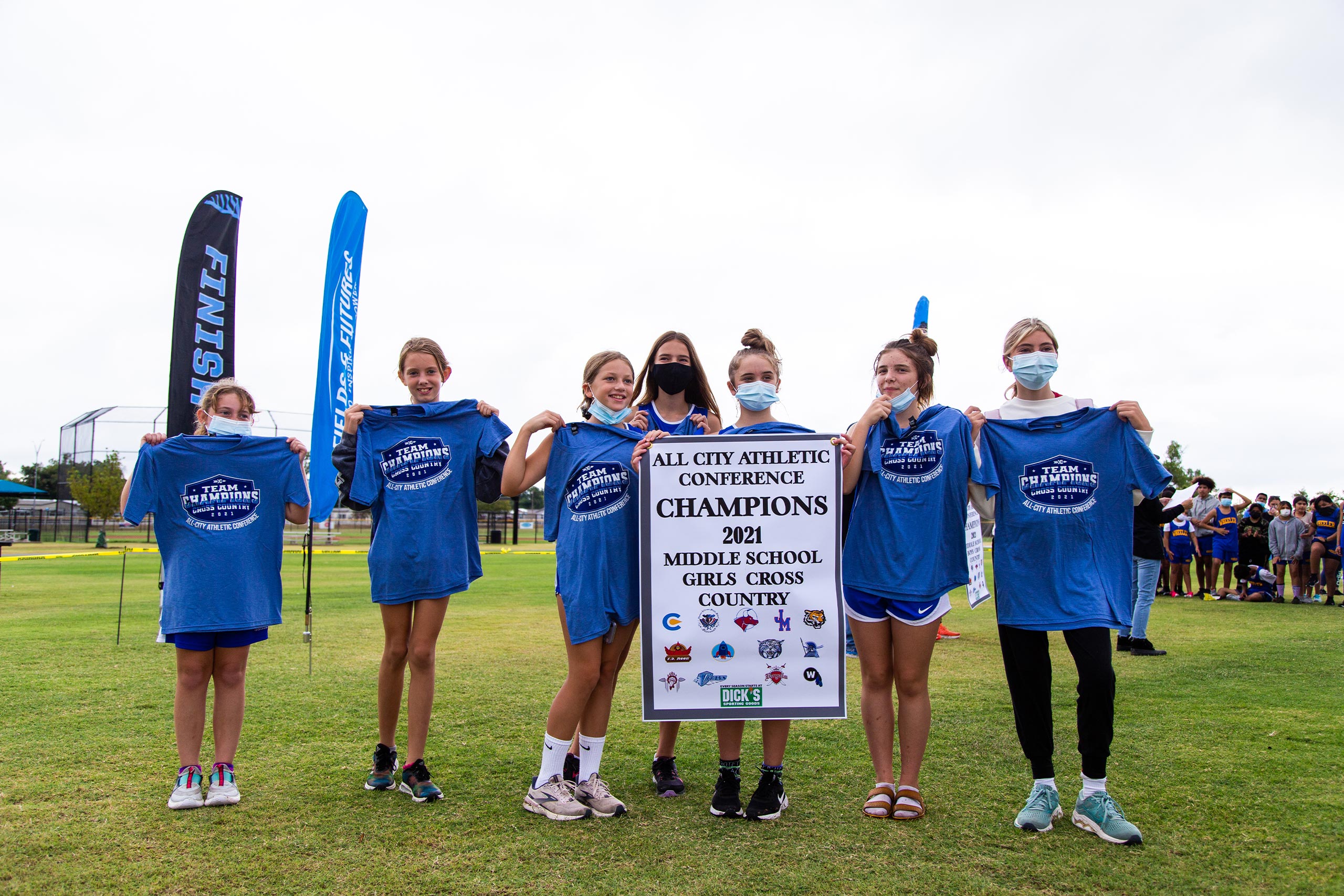 Athletic Conference Middle School Cross Country Championship blog post gallery image of the Classen SAS Middle School girls team holding the team champions banner and wearing team champions t-shirts