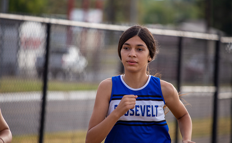 Fields & Futures Simon Greiner Track & Field Program Coach's Interview with John Zehr blog post story image of a female Roosevelt Middle School cross country athlete running in the All-City Athletic Conference cross country meet